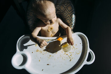 Hohe Winkel Ansicht der hemdsärmeligen Baby Junge essen Essen, während auf Hochstuhl zu Hause sitzen - CAVF54515