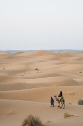 Rückansicht einer auf einem Kamel reitenden Frau in der Wüste Sahara gegen den klaren Himmel - CAVF54518