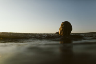 Frau schwimmt im Meer gegen den Himmel bei Sonnenuntergang - CAVF54526