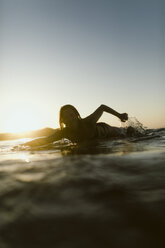 Porträt einer im Meer schwimmenden Frau gegen den Himmel bei Sonnenuntergang - CAVF54527