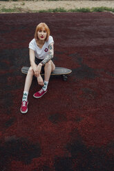 Porträt einer coolen jungen Frau, die auf einem Carver-Skateboard im Freien sitzt - VPIF00961