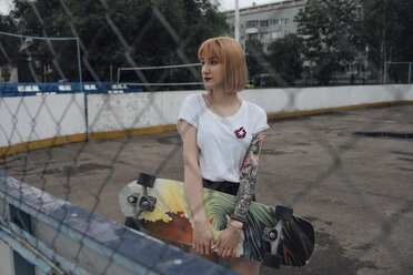 Coole junge Frau hält Carver-Skateboard im Freien - VPIF00970