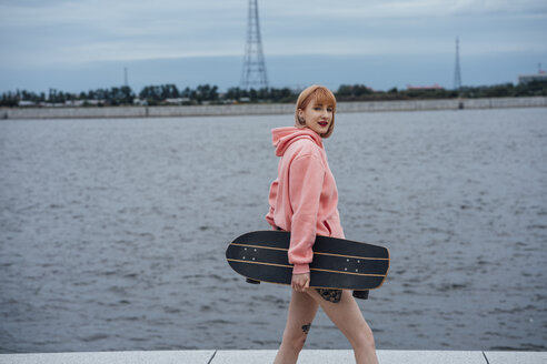 Junge Frau mit Carver-Skateboard am Flussufer - VPIF00980