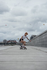 Young woman riding carver skateboard on a promenade - VPIF00990
