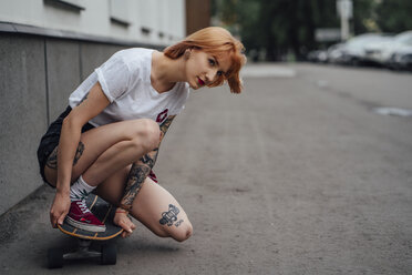 Young woman crouching on carver skateboard on a street - VPIF01003