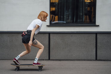 Young woman riding carver skateboard on the sidewalk - VPIF01007