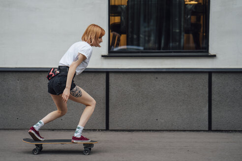 Junge Frau fährt auf dem Gehweg mit einem Carver-Skateboard - VPIF01007