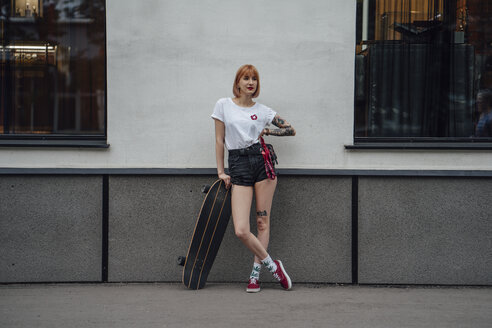 Junge Frau auf dem Bürgersteig stehend mit Carver-Skateboard - VPIF01009