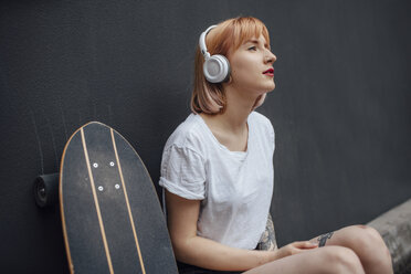 Young woman with skateboard and headphones listening to music - VPIF01012