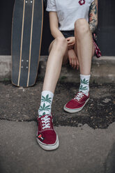 Woman's legs in socks and sneakers sitting next to carver skateboard - VPIF01014