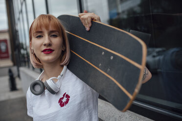 Porträt einer selbstbewussten jungen Frau mit einem Skateboard vor einem Gebäude - VPIF01023