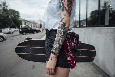 Nahaufnahme einer jungen Frau, die auf dem Bürgersteig ein Skateboard hält - VPIF01025