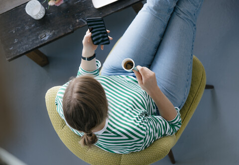 Blick von oben auf eine junge Frau mit Handy und Espresso in einem Café, lizenzfreies Stockfoto