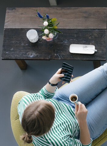 Blick von oben auf eine junge Frau mit Handy und Espresso in einem Café, lizenzfreies Stockfoto