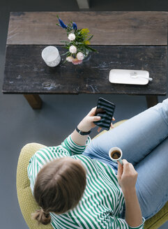Blick von oben auf eine junge Frau mit Handy und Espresso in einem Café - KNSF05299
