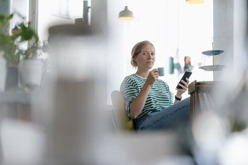 Porträt einer jungen Frau mit Mobiltelefon und Espresso in einem Cafe - KNSF05300