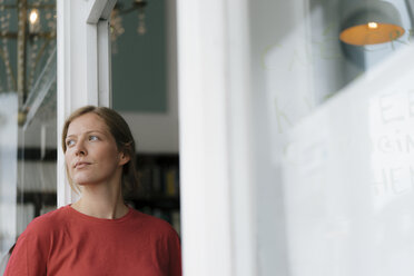 Young woman at French door in a cafe looking around - KNSF05321