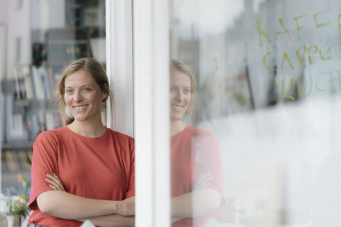 Porträt einer lächelnden jungen Frau an einer französischen Tür in einem Café - KNSF05323