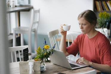 Junge Frau mit Laptop am Tisch in einem Café - KNSF05325