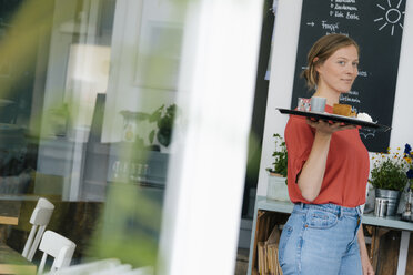 Young woman serving coffee and cake in a cafe - KNSF05336