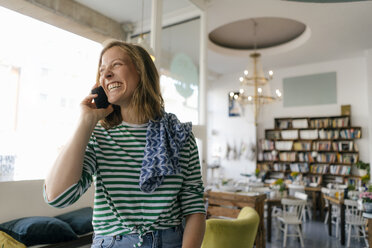 Lachende junge Frau am Handy in einem Cafe - KNSF05352