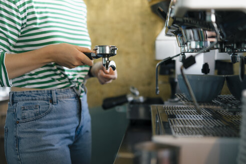 Nahaufnahme einer jungen Frau, die in einem Café Kaffee zubereitet - KNSF05355