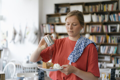 Junge Frau serviert Teller mit Kuchen in einem Cafe, lizenzfreies Stockfoto