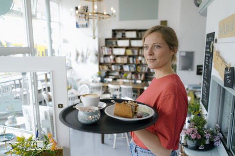 Junge Frau serviert Kaffee und Kuchen in einem Café, lizenzfreies Stockfoto