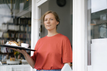 Porträt einer jungen Frau, die Kaffee und Kuchen in einem Café serviert - KNSF05368