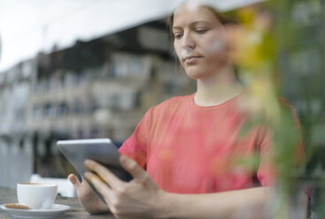 Young woman using tablet at the window in a cafe - KNSF05369