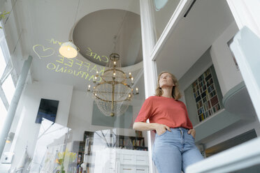 Low angle view of young woman standing in a cafe - KNSF05374