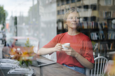 Junge Frau mit Laptop und Kaffeetasse in einem Cafe - KNSF05380