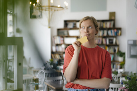 Young woman holding card in a cafe thinking stock photo