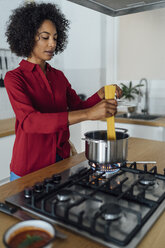 Woman standing in kitchen, preparing spaghetti - BOYF00958