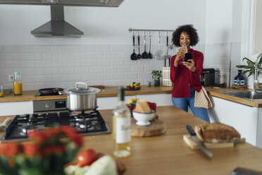 Frau steht in ihrer Küche, macht ein Selfie und trinkt Wein - BOYF00976