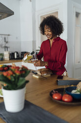 Woman standing in kitchen, pouring herself a glass of white wine - BOYF00982