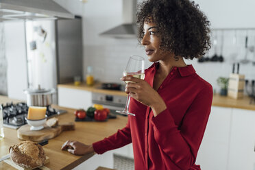 Frau steht in der Küche und trinkt ein Glas Weißwein - BOYF00985