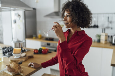 Frau steht in der Küche und trinkt ein Glas Weißwein - BOYF00986