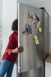 Hungry woman standing in kitchen, searching her fridge - BOYF00992