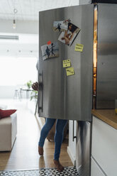 Hungry woman standing in kitchen, searching her fridge - BOYF00994