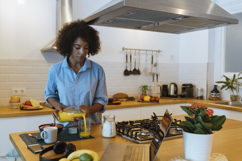 Frau frühstückt in ihrer Küche und trinkt Orangensaft, lizenzfreies Stockfoto