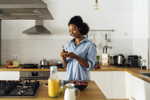 Frau in ihrer Küche am Morgen, die Notizen schreibt, lizenzfreies Stockfoto