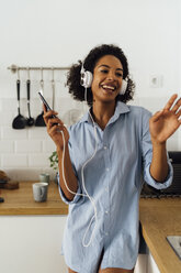 Woman dancing and listening music in the morning in her kitchen - BOYF01041