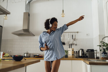 Woman dancing and listening music in the morning in her kitchen - BOYF01044