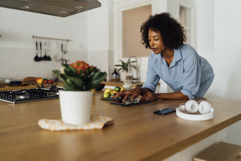 Frau mit digitalem Tablet und einem gesunden Frühstück in ihrer Küche - BOYF01054