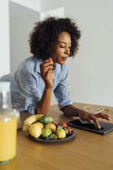 Frau mit digitalem Tablet und einem gesunden Frühstück in ihrer Küche - BOYF01057