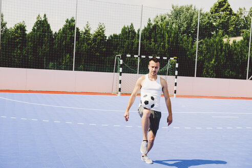 Junger Mann beim Fußballtraining auf dem Platz in voller Länge an einem sonnigen Tag - CAVF54564