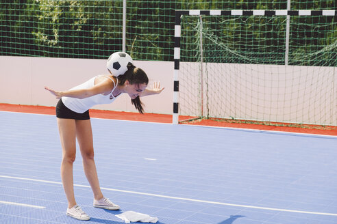 Junge Frau balanciert Fußball auf dem Rücken auf einem Platz in voller Länge - CAVF54566