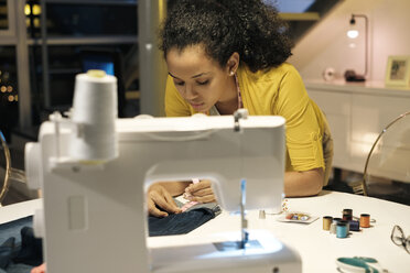 Female entrepreneur measuring jeans on table in office - CAVF54596