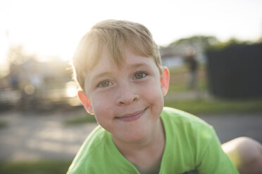 Porträt von niedlichen lächelnden Jungen spielen auf dem Spielplatz bei Sonnenuntergang - CAVF54628